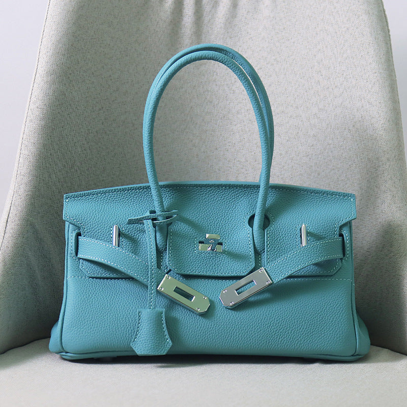 Front view of a Northern Blue JPG Birkin inspired handbag in textured top grain cowhide leather, featuring silver-tone lock closure hardware and a matching clochette.