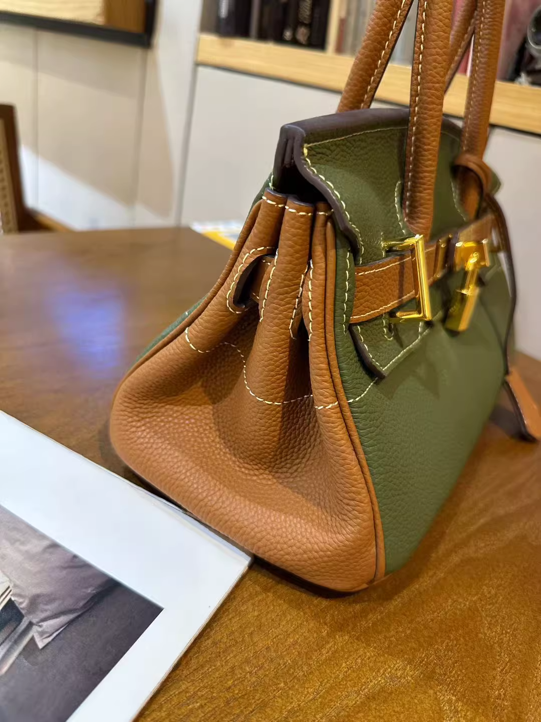 Side view of a Green and Brown bi-color JPG Birkin inspired handbag in top grain leather, featuring elegant golden hardware and a structured gusset design.