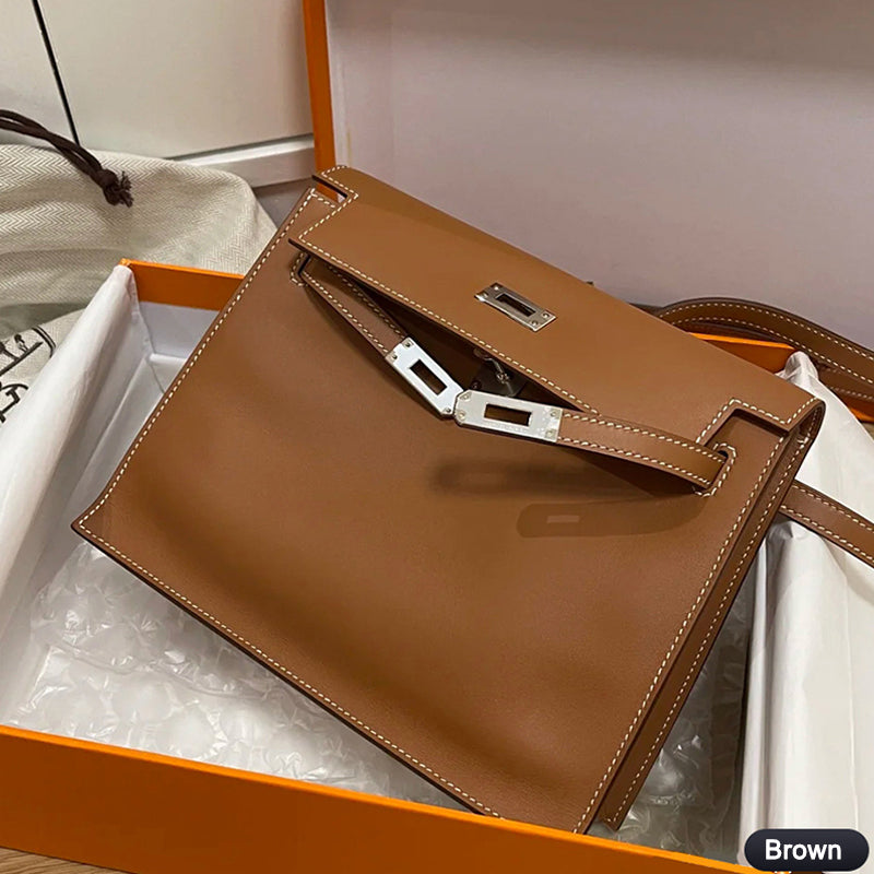 A brown top grain leather Kelli Danse shoulder bag with white contrast stitching and silver hardware, presented in a signature orange gift box.