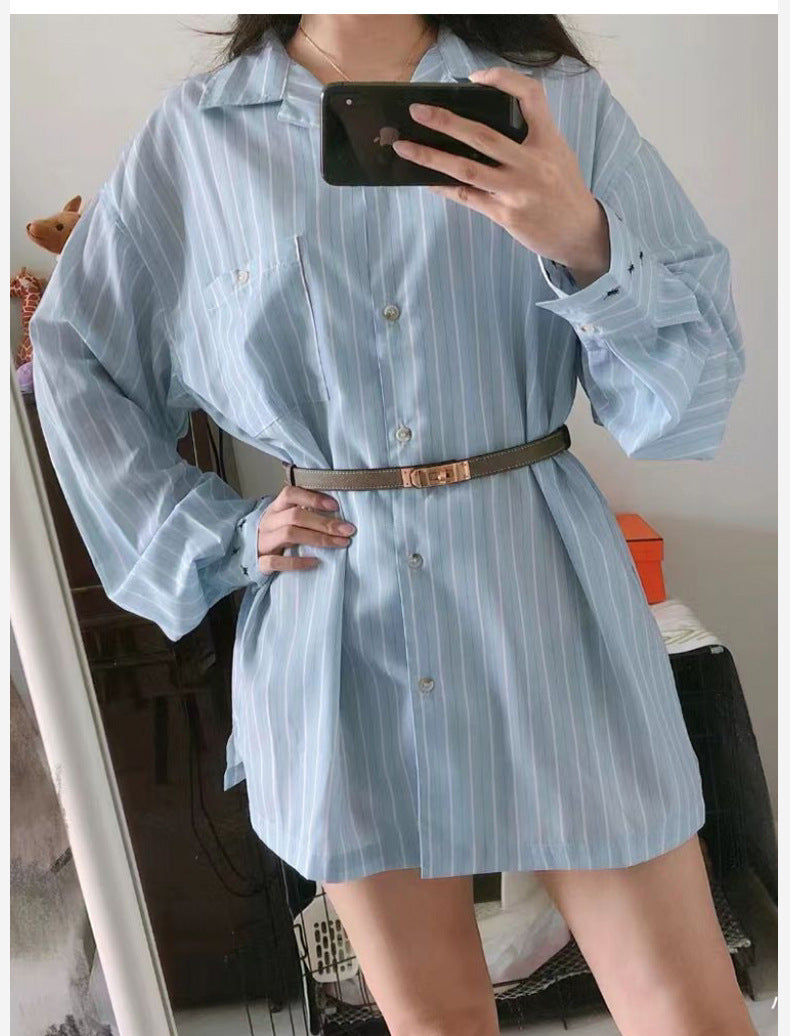 Taupe Kelli leather belt cinching the waist of an oversized light blue striped shirt to create a flattering silhouette
