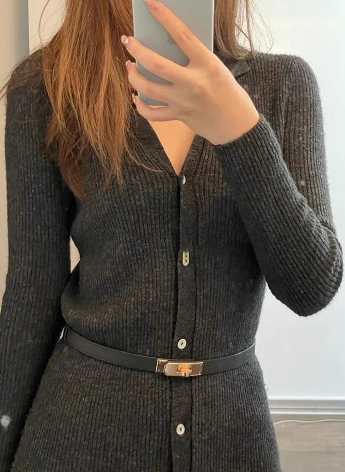 Close-up of a black Kelli leather belt with rose gold hardware styled over a dark charcoal ribbed knit cardigan dress