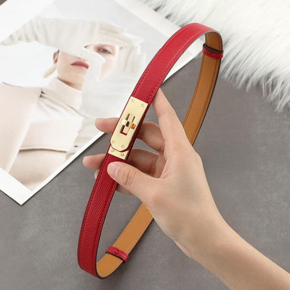 Close-up shot of a vibrant red Epsom leather Kelli belt featuring a polished golden turn-lock plate and tan leather interior
