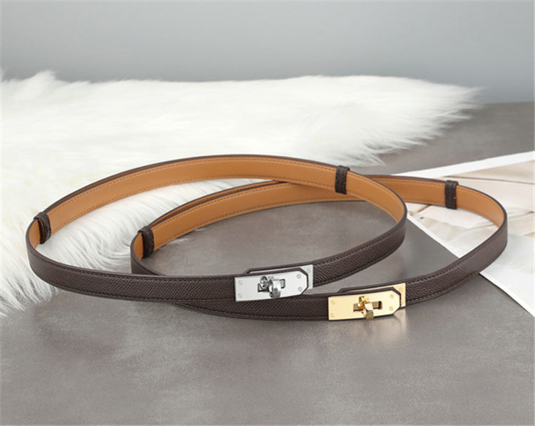 Two Etoupe Epsom leather Kelli belts, one with golden hardware and one with silver hardware, showcasing the versatile grey-brown tone