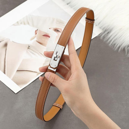 A Golden Brown Epsom leather Kelli belt with white contrast stitching and a polished silver-tone turn-lock hardware held by a hand