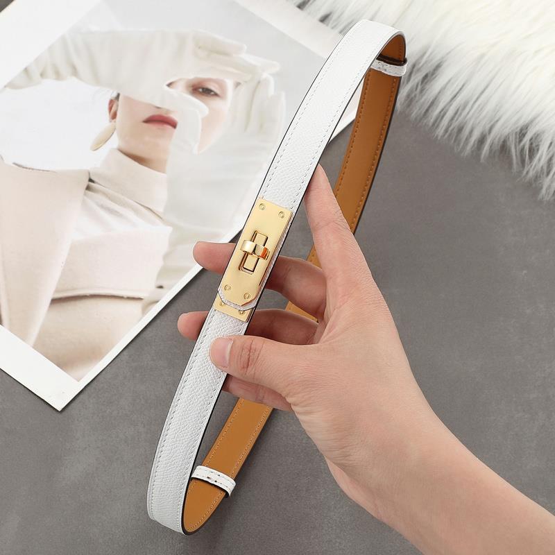 Close-up of a crisp white Epsom leather Kelli belt with a polished golden turn-lock hardware and tan leather lining.