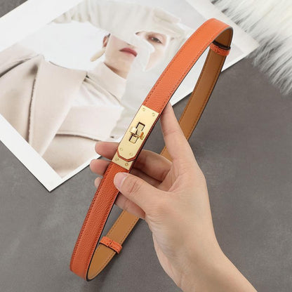Close-up of a classic orange Epsom leather Kelli belt featuring a polished golden turn-lock hardware and tan leather interior.