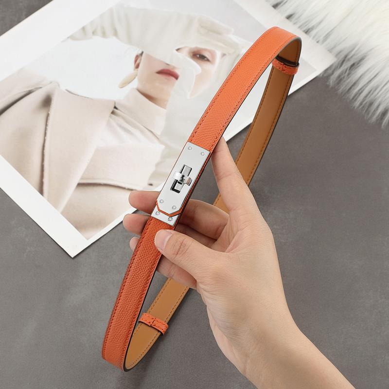 A classic orange Epsom leather Kelli belt featuring a polished silver-tone turn-lock plate and tan leather lining.