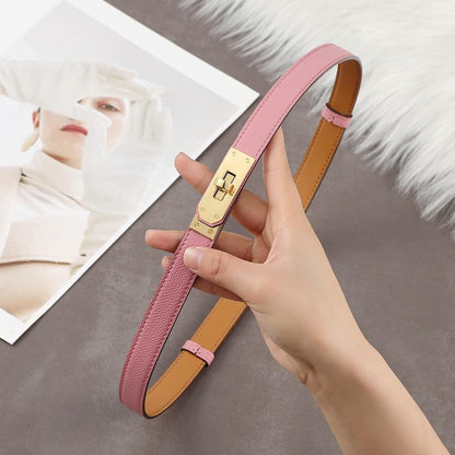 Close-up of a soft pink Epsom leather Kelli belt with a polished golden turn-lock hardware and tan leather interior.