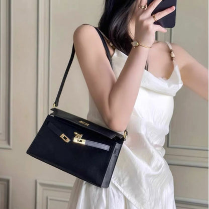 Model wearing a black split leather inspired Kelly Elan shoulder bag with gold hardware as an underarm bag.