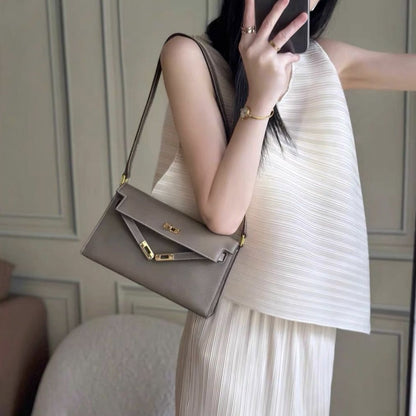 Model wearing taupe split leather inspired Kelly Elan shoulder bag with gold hardware as a chic underarm bag.