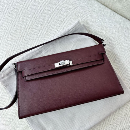 Wine red split leather inspired Kelly Elan shoulder bag with silver hardware on a white dust bag.