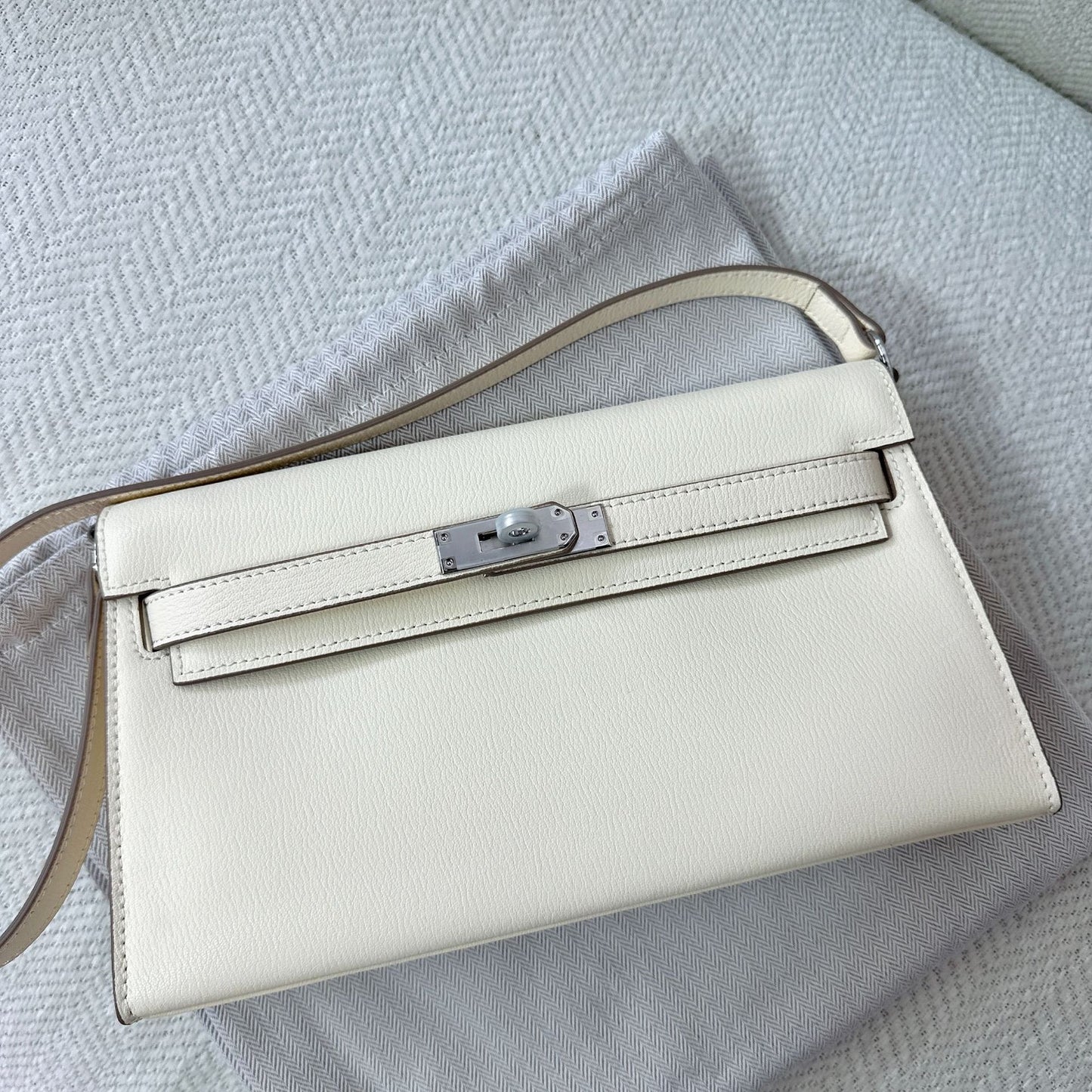 Off-white split leather inspired Kelly Elan shoulder bag with silver hardware on a white dust bag.