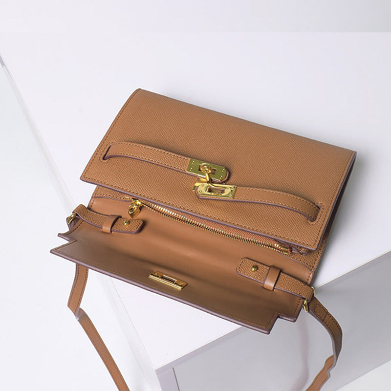 An angled interior view of a tan inspired Kelly to go wallet in cowhide leather, showing the open flap, functional golden Kelli closure straps, and a secure zippered compartment.