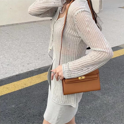 A brown textured cowhide leather Kelly long wallet worn crossbody, highlighting its signature golden Kelly closure and versatile everyday design.
