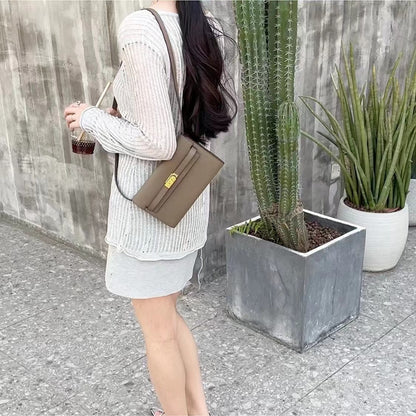 Lifestyle shot of a model wearing an Apricot Grey inspired Kelly to go wallet as a shoulder bag, paired with a white knit top for an elegant, minimalist aesthetic.