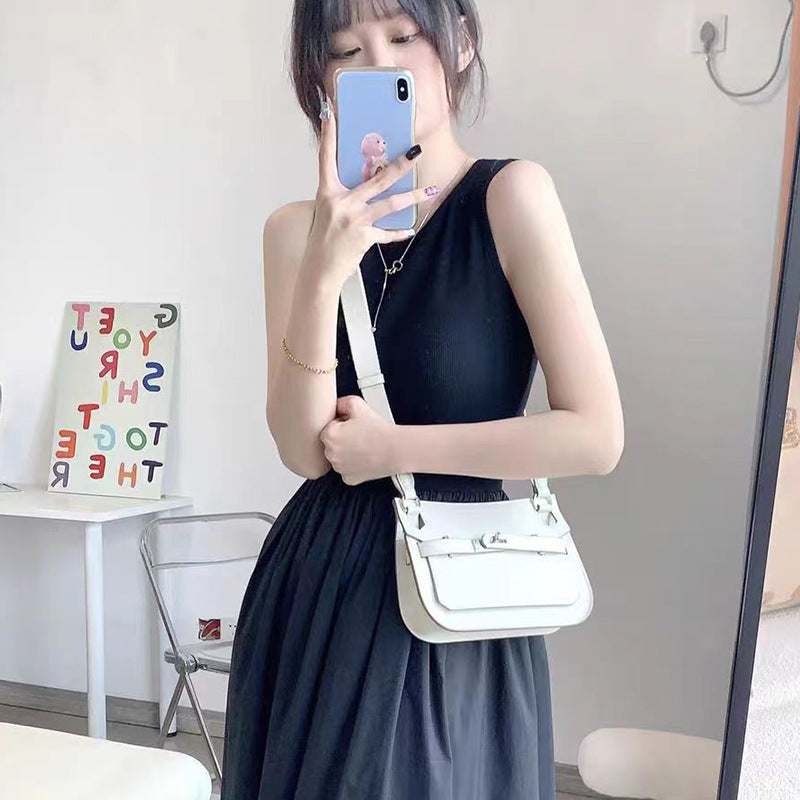 A woman styling a white leather Gypsy crossbody bag with a black one-shoulder dress, demonstrating its perfect size and elegant minimalist look.