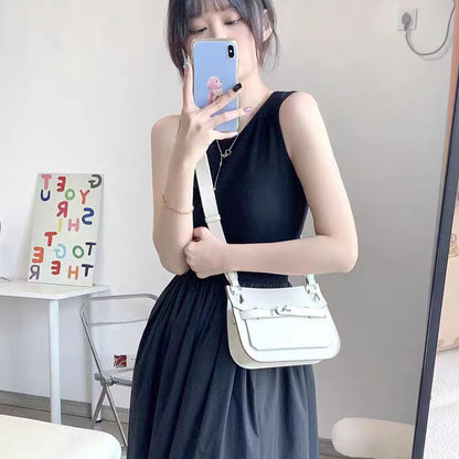 A woman styling a white leather Gypsy crossbody bag with a black one-shoulder dress, demonstrating its perfect size and elegant minimalist look.