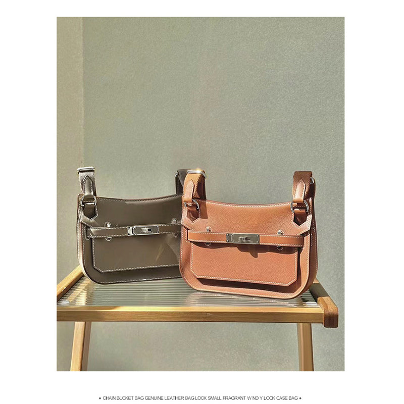Two Gypsy leather shoulder bags in Taupe and Golden Brown, placed on a wooden stand to showcase the different color options and premium texture.