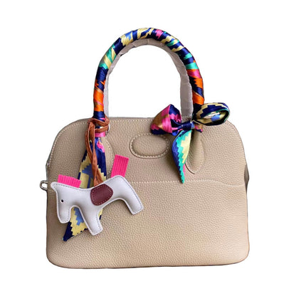 Beige top grain leather shell bag with colorful silk scarf and horse charm.