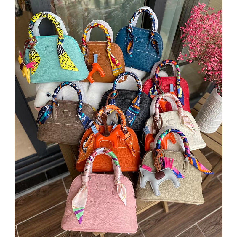 Colorful collection of top grain leather bowling shell bags with silk scarves.