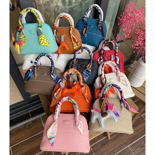 Colorful collection of top grain leather bowling shell bags with silk scarves.