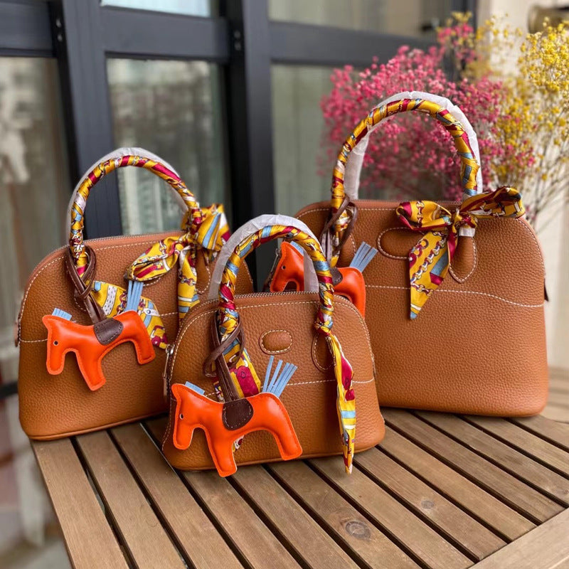 Three sizes of tan leather bowling shell bags comparison with silk scarves