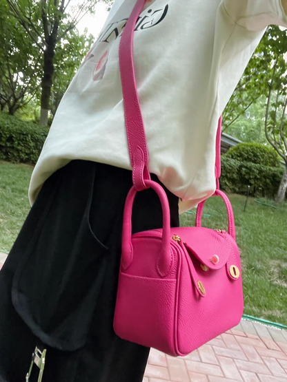 Model wearing a raspberry red top grain leather Lindy bag as a shoulder bag