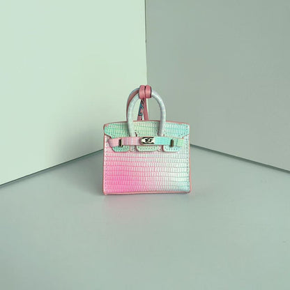 Front view of a colorful gradient mini Birkin handbag charm with a luxury crocodile embossed texture and silk scarf handle.