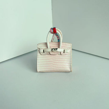 Front view of a pink gradient mini Birkin handbag charm featuring a luxury crocodile embossed texture and silk scarf handle.