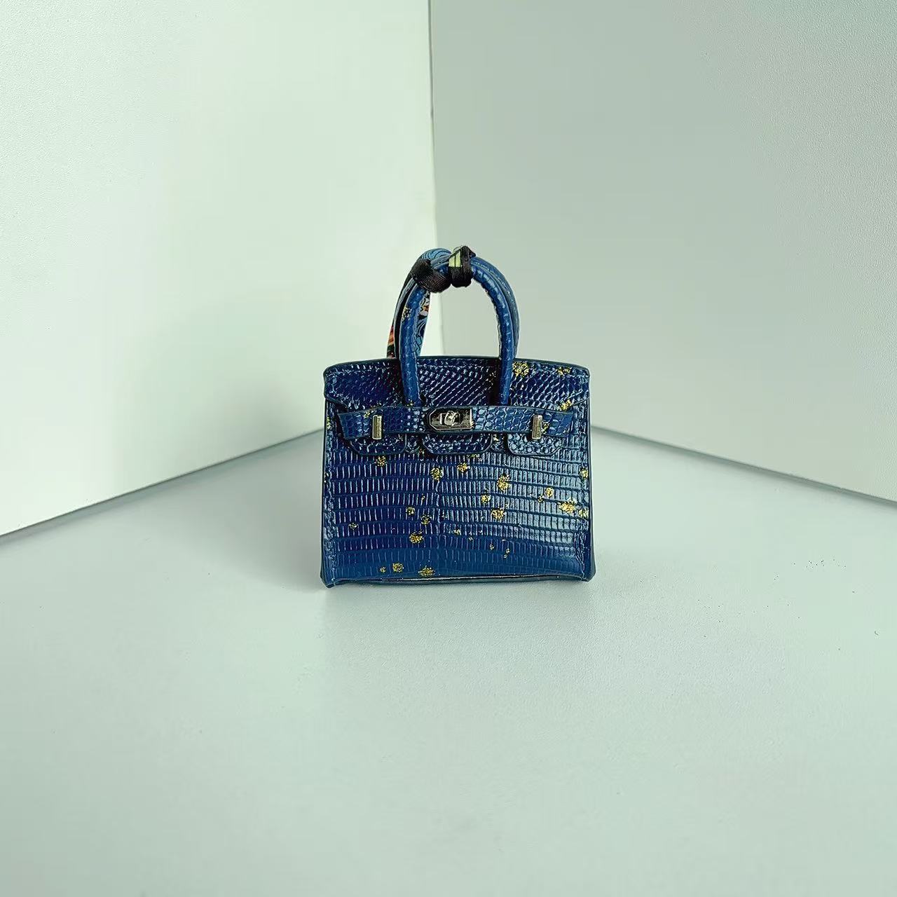 Front view of a Dark Blue with Speckle mini Birkin handbag charm featuring a luxury crocodile embossed texture and silk scarf handle.