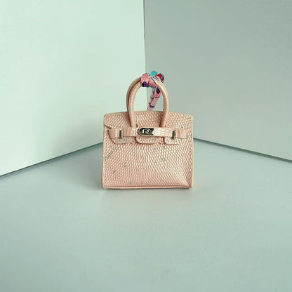 Front view of a Pink with Speckle mini Birkin handbag charm featuring a luxury crocodile embossed texture and silk scarf handle.