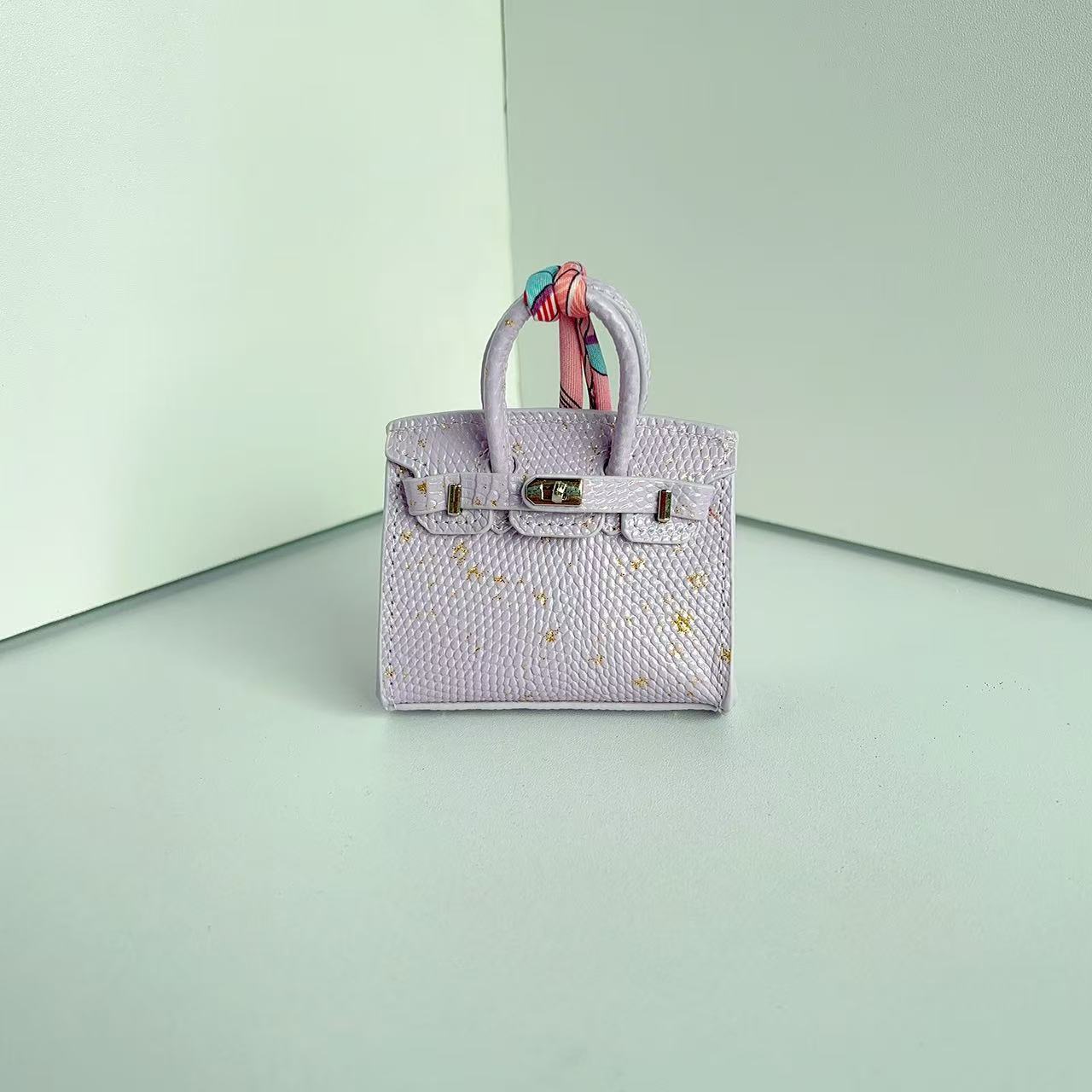Front view of a Light Purple with Specklet mini Birkin handbag charm featuring a luxury crocodile embossed texture and silk scarf handle.