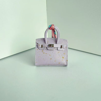 Front view of a Light Purple with Specklet mini Birkin handbag charm featuring a luxury crocodile embossed texture and silk scarf handle.