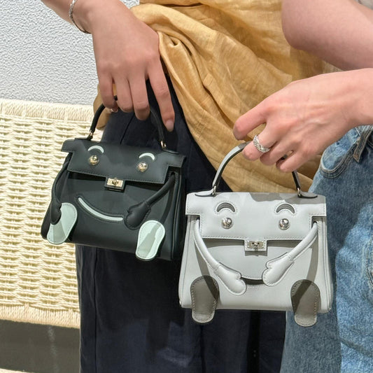 Two Inspired Kelli Doll mini bags in smooth leather featuring playful face designs and movable arms.