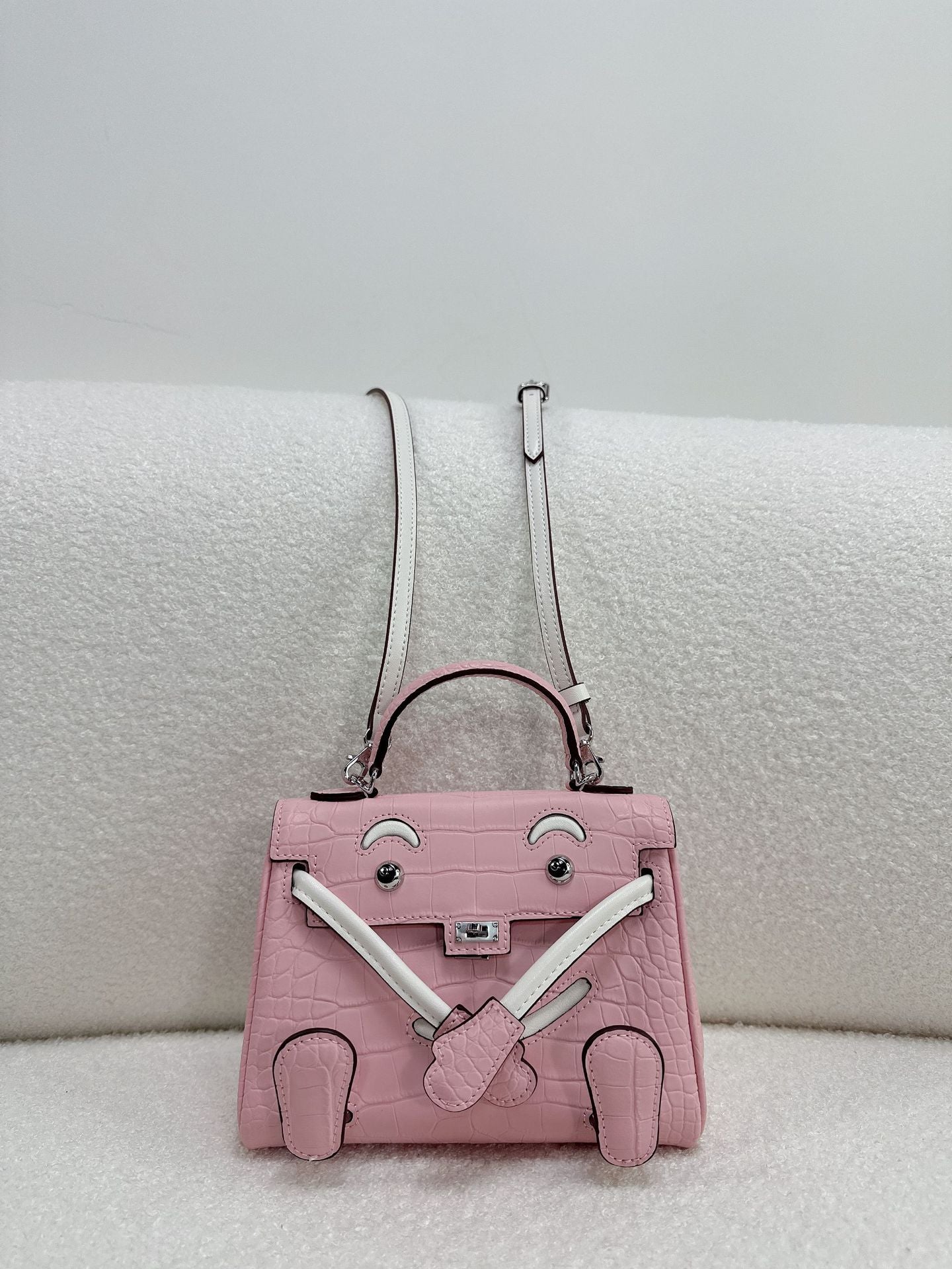 Chic pink and white leather doll bag with unique character design for a trendy look.