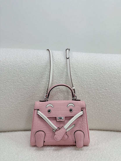 Chic pink and white leather doll bag with unique character design for a trendy look.
