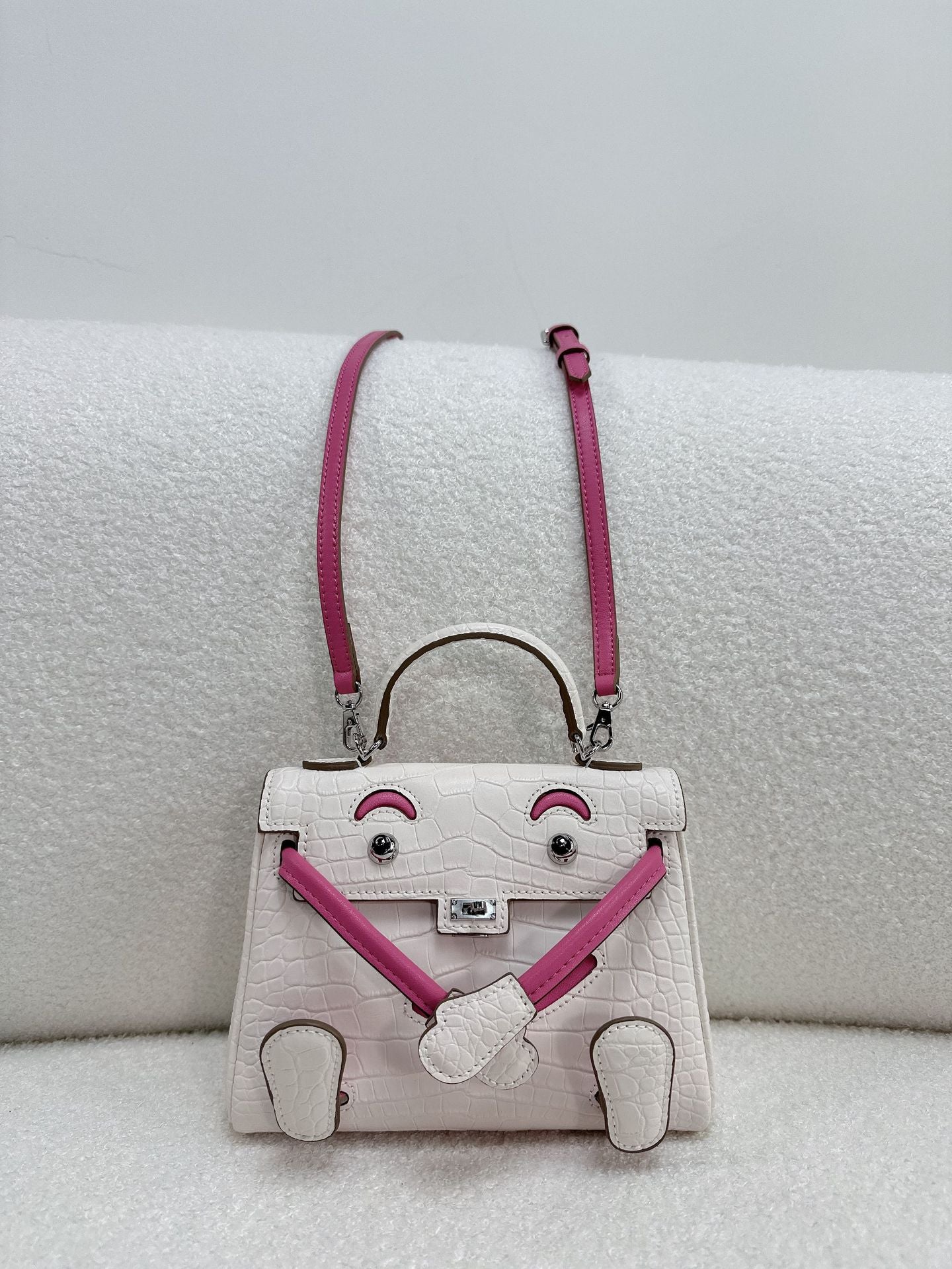  Unique white and pink croc-embossed leather doll bag with adjustable limbs and top handle.