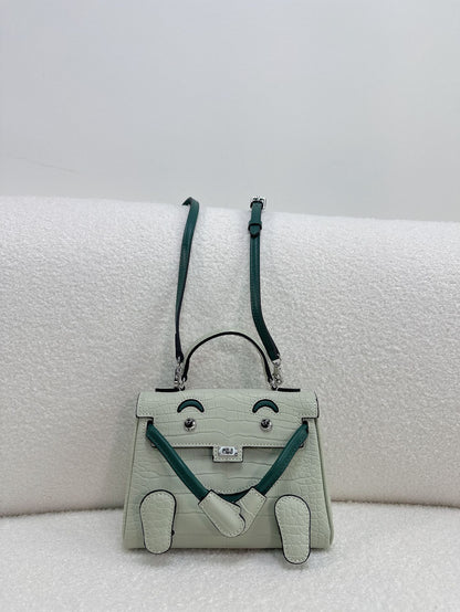 Unique light green leather doll bag with quirky face design and top handle.