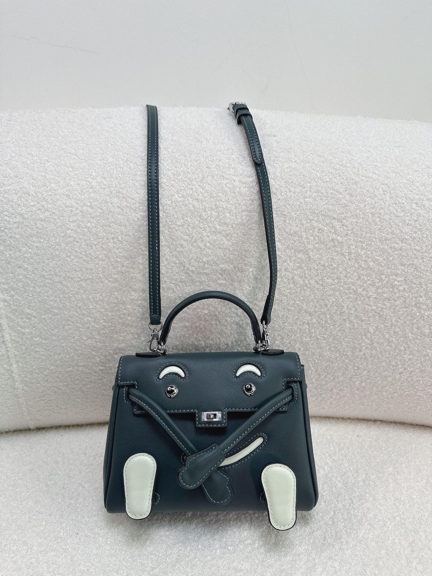 Inspired Kelli Doll mini bag in dark green smooth leather with contrasting white limbs and face design.