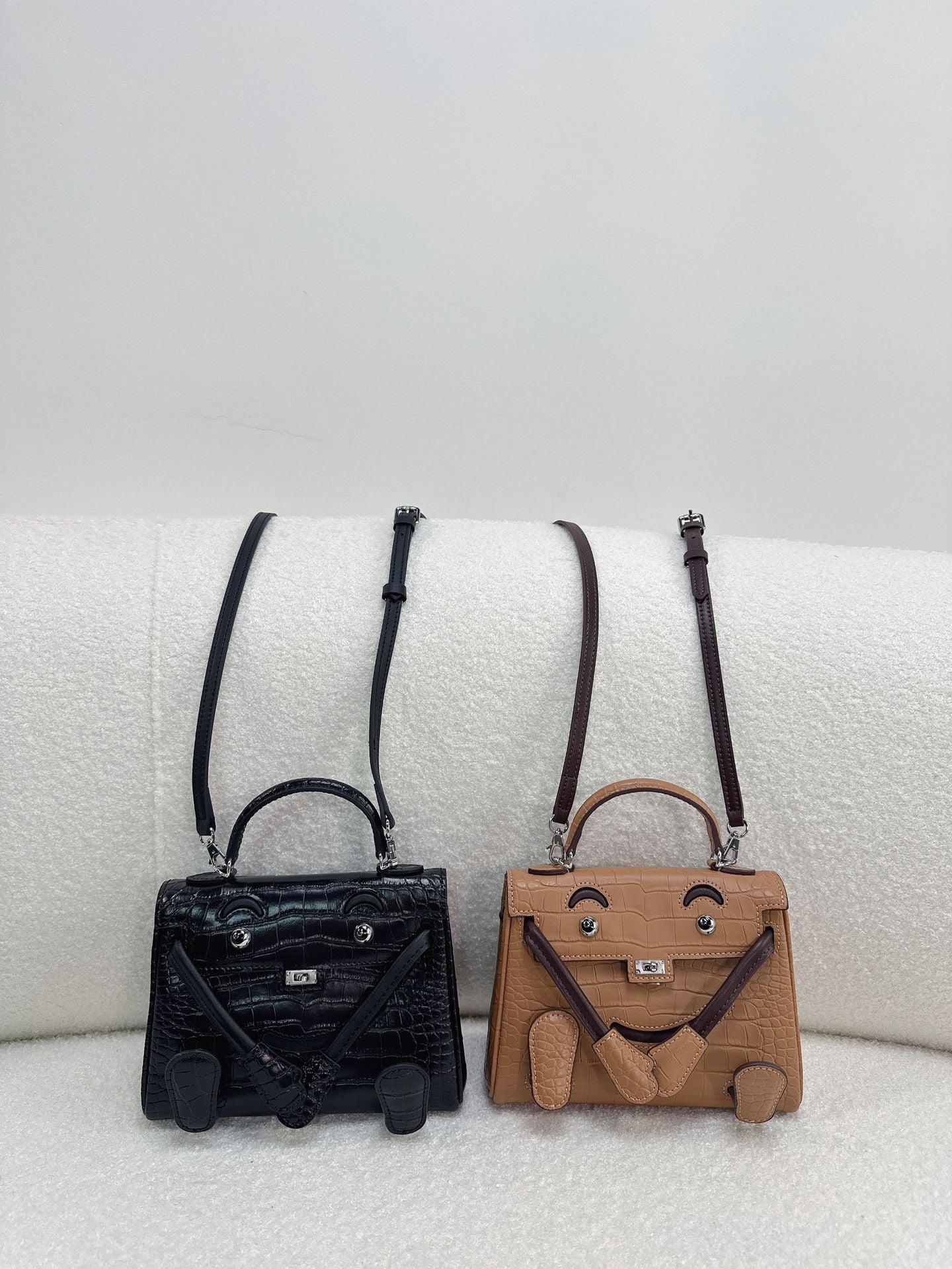  Chic black and brown leather Kelli Doll bags with unique face designs and adjustable straps.