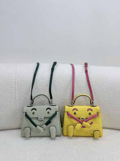 Playful light green and yellow leather Kelli Doll bags with unique face designs and adjustable straps.
