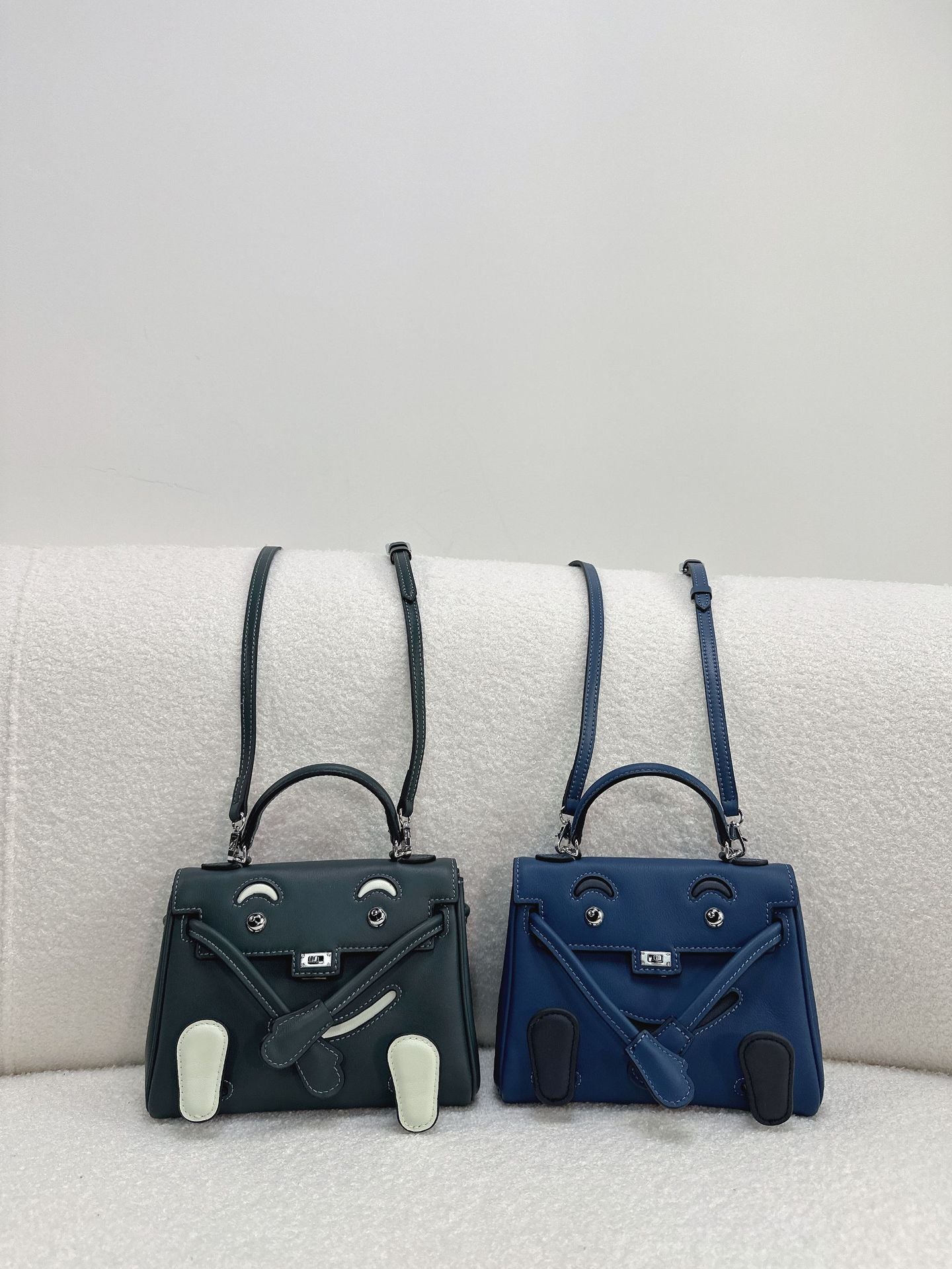  Sophisticated dark green and blue leather Kelli Doll bags with unique face designs and adjustable straps.