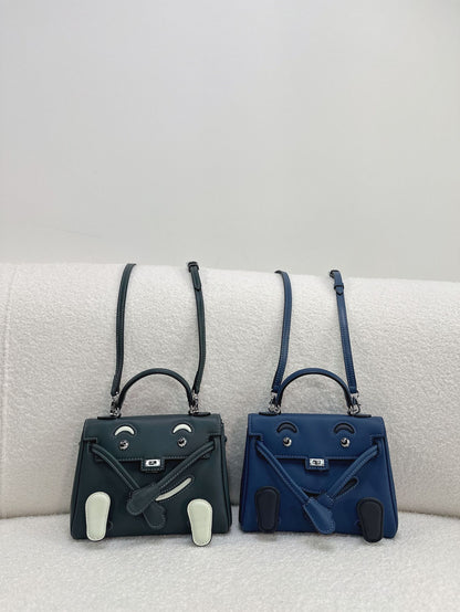  Sophisticated dark green and blue leather Kelli Doll bags with unique face designs and adjustable straps.