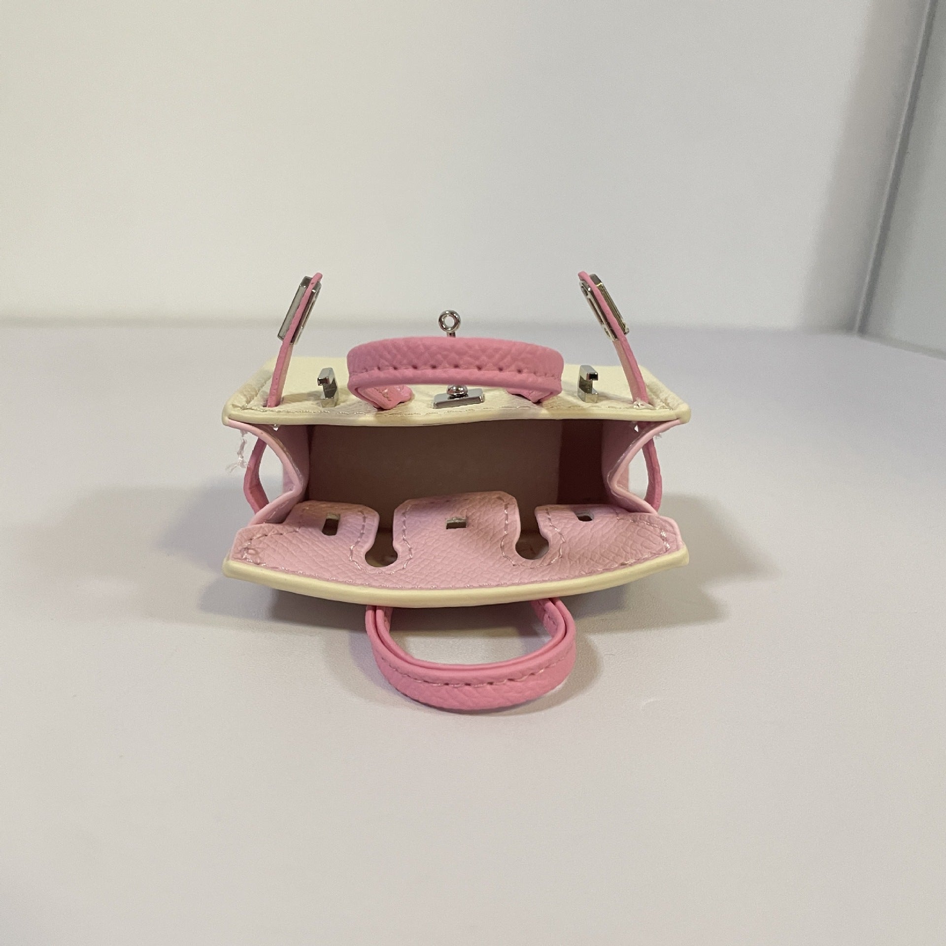 Open view of tri-color off-white and pink mini Birkin AirPods case.