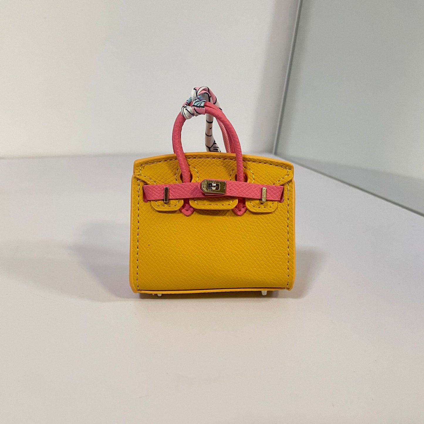 Two-tone yellow and watermelon red mini Birkin bag charm with silk scarf handle.