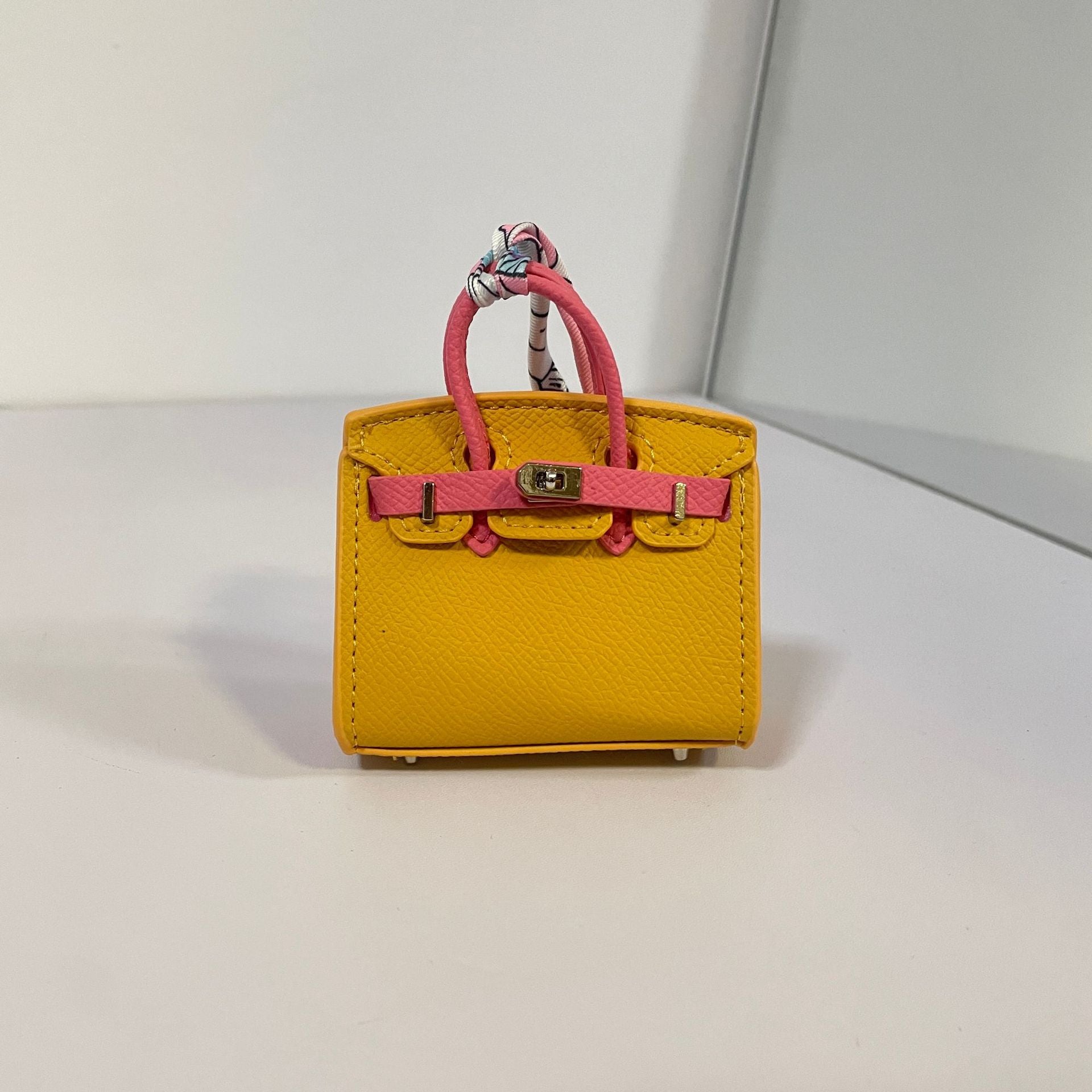 Two-tone yellow and watermelon red mini Birkin bag charm with silk scarf handle.