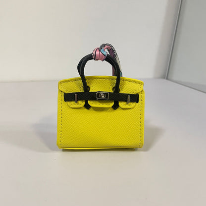 Two-tone yellow and black mini Birkin bag charm with a pink silk Twilly scarf.