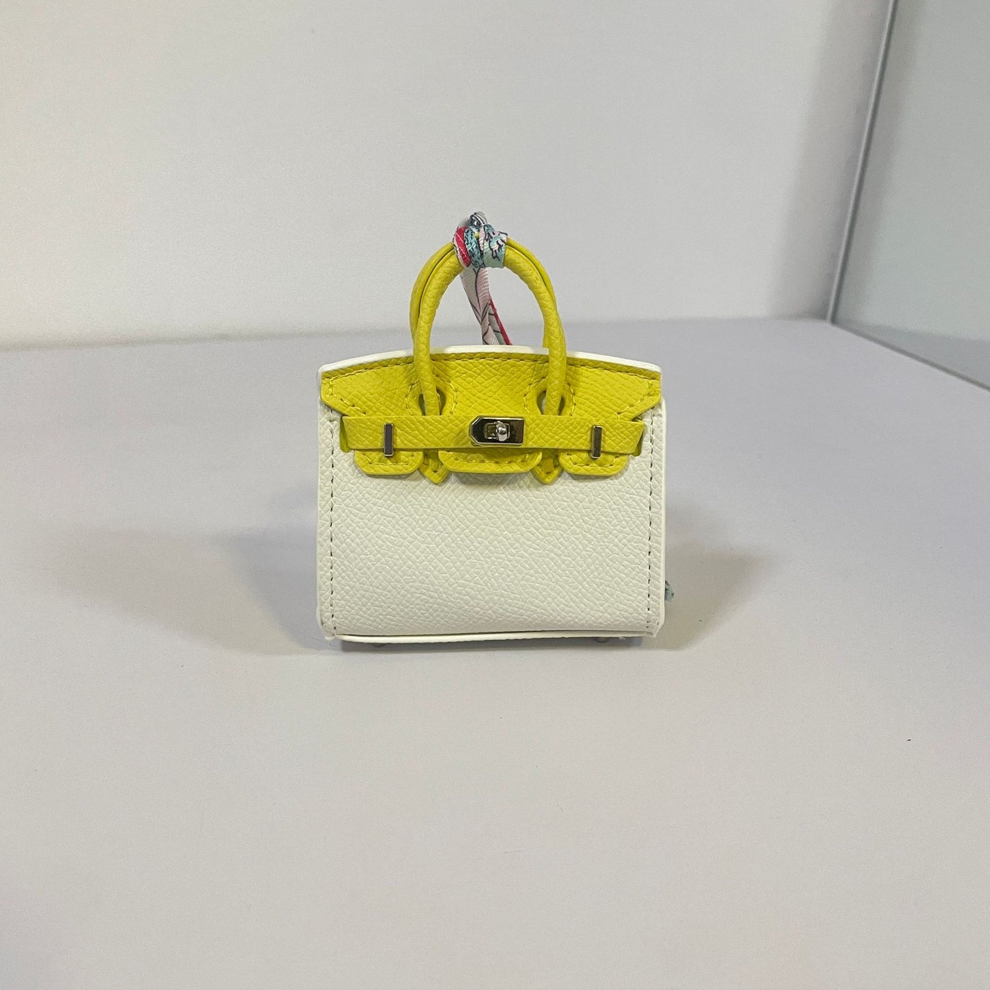 Two-tone white and yellow mini Birkin bag charm with silver hardware.