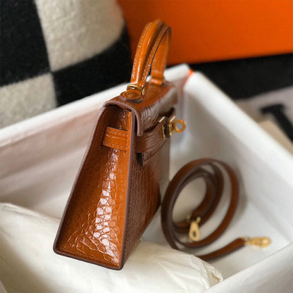 Side view of Gold Brown croc embossed leather mini Kelly handbag with top handle and detachable shoulder strap.