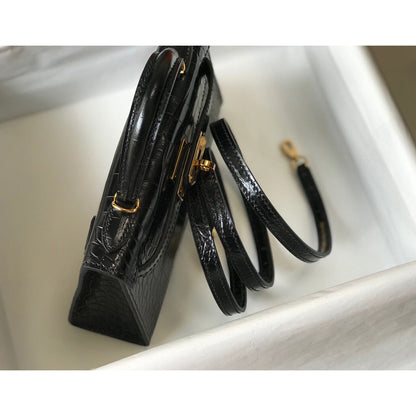 Top-down side view of black croc embossed leather mini Kelly bag with gold buckle and long shoulder strap.